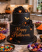 Black Halloween cake made with black Beau products sugarpaste, with decorative elements located on a kitchen counter. 