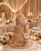 Four-tiered wedding cake covered with Mink coloured sugarpaste by Beau products, with floral decorations in a elegant banquet hall setting.