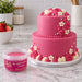 A tub of Beau's strawberry flavoured fondant sitting on a marble surface in front of a strawberry coloured cake.